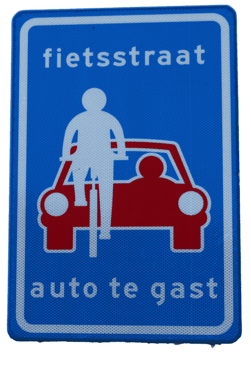 Blue road sign with a white silhouette of a cyclist in front of a red car with the text reading "fietsstraat, auto te gast," to indicate this is a cyclist priority area.