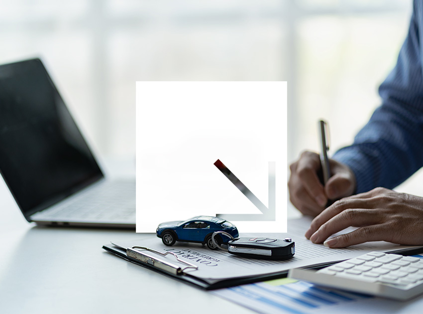 Person working at a desk with a laptop, documents, toy car, and car key.