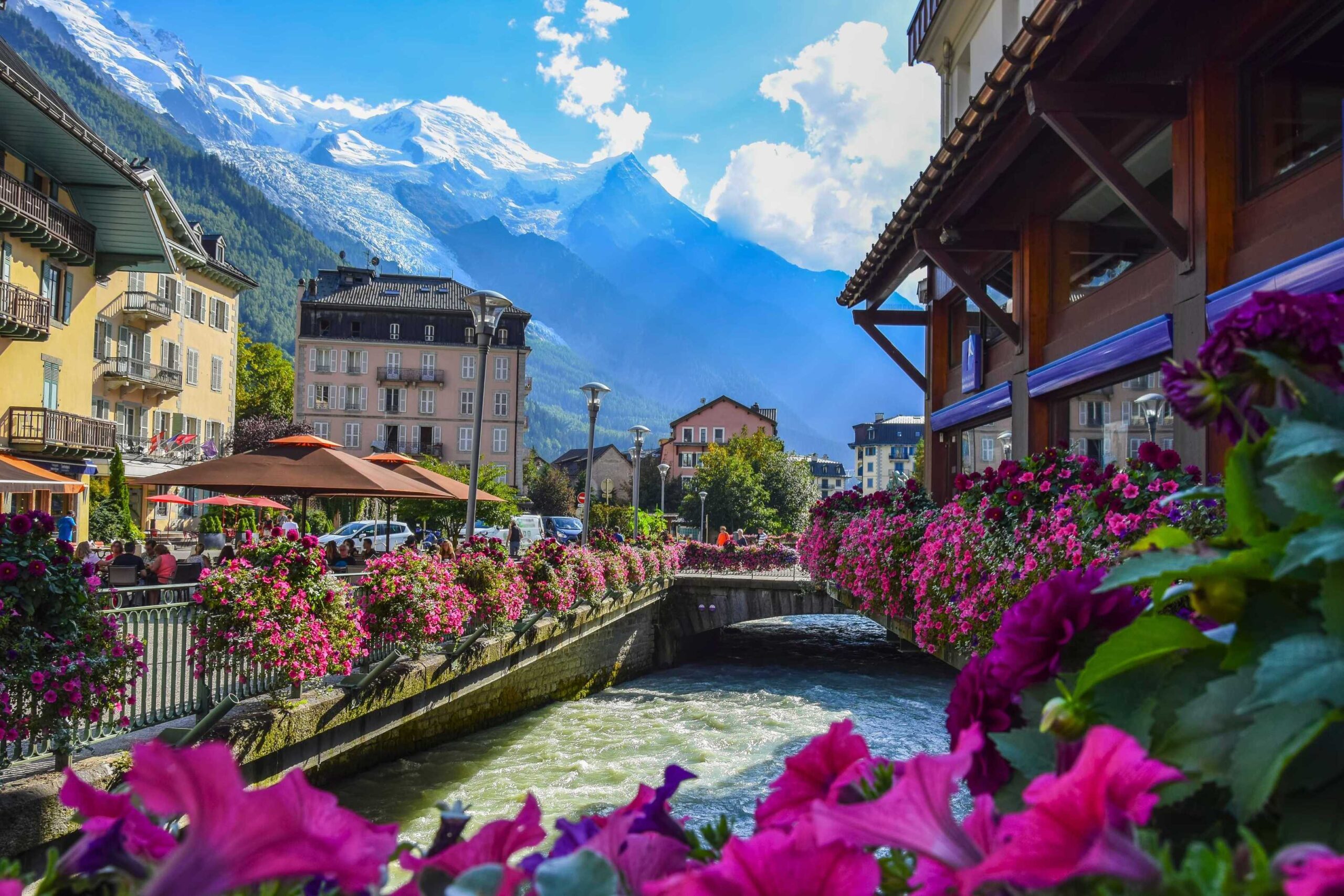 View of the Arve river and Mont-Blanc massif from the centre of Chamonix under a bright blue sky.