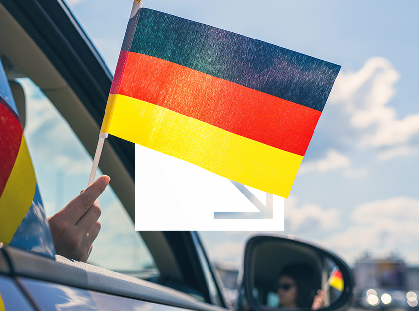 German flag held from a car window on a bright day, representing international driving with optional car hire excess insurance.