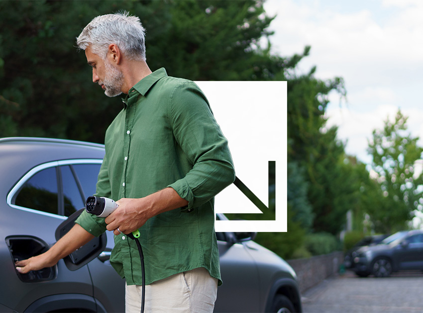Man plugging an electric car into a charging port, illustrating how car hire excess insurance still applies to EV rentals.